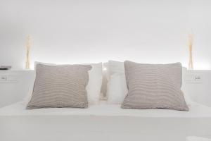 Una cama blanca con cuatro almohadas. en Golden's Suite nel cuore di Modena, en Módena