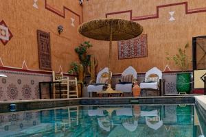a pool with chairs and an umbrella next to a building at Riad Parfums de OUARZAZATE in Ouarzazate