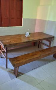 a wooden table and bench with a bowl of flowers on it at Apto I com cozinha em Macapa in Macapá