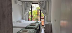 two beds in a room with a window at Varandas do Mar pé na areia in Cumbuco +16 photos