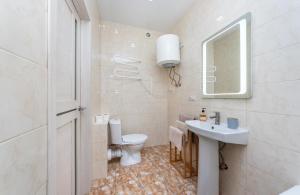 Un baño con inodoro, lavabo y espejo. en ЖК "Ривьера", en Kiev