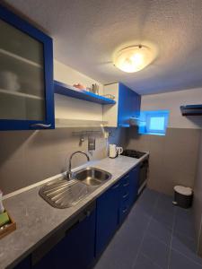 a kitchen with blue cabinets and a sink at Apartman u centru Komiže in Komiža