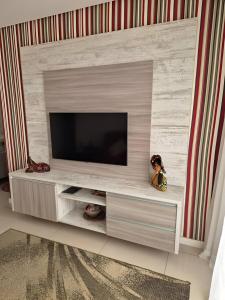 a entertainment center with a television in a living room at Varandas do Mar pé na areia in Cumbuco