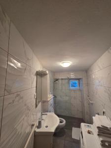 a white bathroom with a sink and a toilet at Apartman u centru Komiže in Komiža