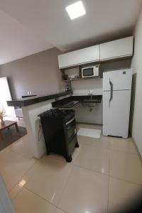 une petite cuisine avec un réfrigérateur et un micro-ondes dans l'établissement Casa Completa 01 com AR - Encantos de Arraial, à Arraial do Cabo 5 autres photos