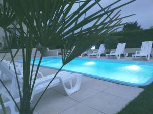 a swimming pool with lounge chairs and a palm tree at Pensjonat Dolce Vita & SPA in Ustronie Morskie
