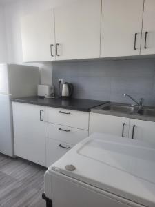 a white kitchen with a sink and white cabinets at Panorama in Dzierżoniów +7 photos