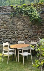 a wooden table and chairs in front of a stone wall at Il cuore della Valtellina - giardino privato in Caiolo