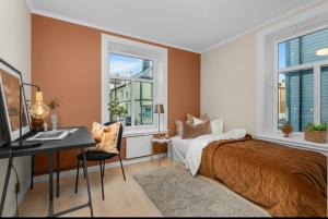 Un dormitorio con una cama, un escritorio y ventanas. en Solsiden trondheim 3roms, en Trondheim