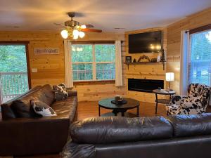 a living room with a leather couch and a television at Ole Bud Cabin by American Patriot Getaways in Walnut Grove