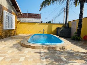 a small swimming pool in a courtyard with a yellow wall at Casa da vovó Marta in Itanhaém