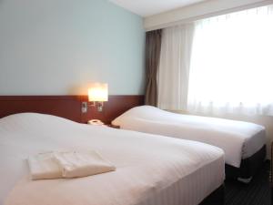 two beds in a hotel room with a window at Paradis Inn Sagamihara in Sagamihara