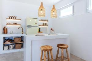 a kitchen with a counter with stools and a refrigerator at Syrolia Village - Phos in Kini