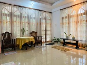 a dining room with a table and chairs and windows at Mango Villa in Matara