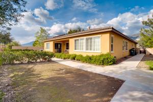 a yellow house with a driveway at Single-Story San Bernardino Home with Valley Views! in San Bernardino