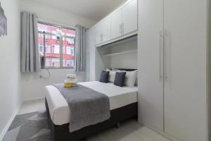 a bedroom with a bed with white walls and a window at Conforto a 6min da praia de Copacabana - BR801 in Rio de Janeiro