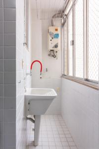 a white bathroom with a sink and a window at Conforto a 6min da praia de Copacabana - BR801 in Rio de Janeiro
