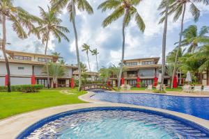 un complejo con piscina y palmeras en PF112 Magnífico apartamento frente al mar con 2 suites - Praia do Forte, en Praia do Forte