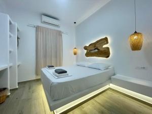 1 dormitorio con 1 cama blanca y suelo de madera en Alexandra Suites & Rooms - MYKONOS PORT, en Mykonos ciudad