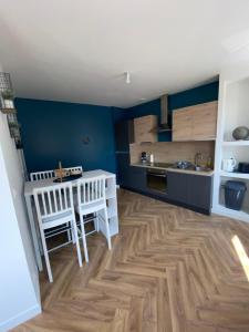 a kitchen with blue walls and a wooden floor at Welc'home in Saint-Valéry-en-Caux