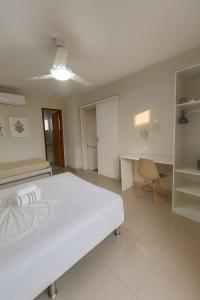 une grande chambre blanche avec un lit et un bureau dans l'établissement Casa Completa 01 com AR - Encantos de Arraial, à Arraial do Cabo