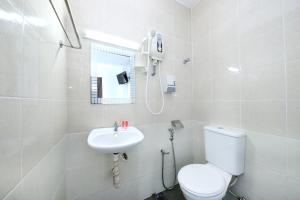 a white bathroom with a toilet and a sink at Midah Inn Puchong in Puchong