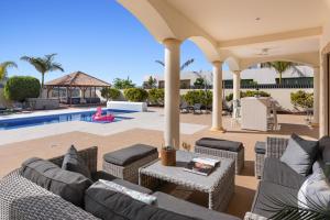 a patio with wicker furniture and a swimming pool at Karat Villa Lusso in Adeje