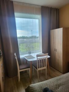 a bedroom with a table and chairs and a window at Transhostel IRIS in Narva