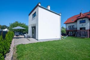 a white house with a patio and a yard at Nemo - apartament, domek w Gaskach in Gąski