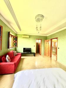 a living room with a red couch and a tv at Villa H in Oulad Snaguia +32 photos