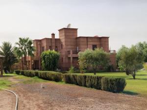 a building with a row of hedges in front of it at Villa H in Oulad Snaguia