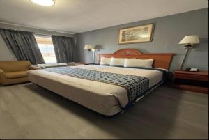 a hotel room with a large bed and a chair at Budget Inn in Magnolia +2 photos