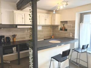 eine Küche mit weißen Schränken und einer Theke mit 2 Stühlen in der Unterkunft Appartement 2 Chambres in Carcassonne