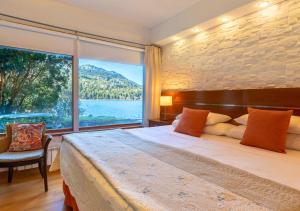 a bedroom with a bed and a large window at Costa Serena Aparts & Spa in Villa La Angostura