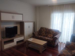 a living room with a couch and a tv at Piso Ría de Ribadeo in Ribadeo