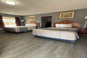 two beds in a hotel room with wood floors at Budget Inn in Magnolia