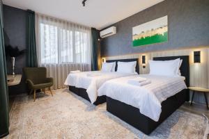 una habitación de hotel con dos camas y una silla en А17 Plovdiv Apartments - Close to University hospitals, Rowing Channel and Mall Plovdiv, en Plovdiv
