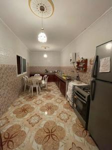 Una cocina con refrigerador y una mesa con sillas. en Dar RACHIDA RIFIYA Estudio privado, en Tánger