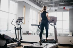 a woman on a treadmill in a gym at Delta Hotels by Marriott Saguenay Conference Centre in Saguenay
