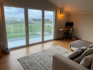 een woonkamer met een bank en een groot raam bij Beachfront Costa Nova Villa - 2BR Apartment in Gafanha da Encarnação