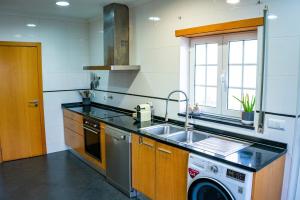 een keuken met een spoelbak en een wasmachine bij Beachfront Costa Nova Villa - 2BR Apartment in Gafanha da Encarnação +23 foto's
