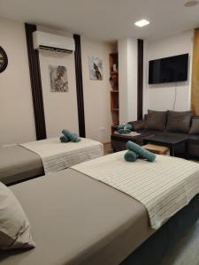 a hotel room with three beds and a couch at Good Mood Apartments & Parking 2 in Plovdiv