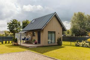 a small house with a black roof on a yard at Tiny house Sigulda in Sigulda