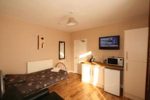 Zimmer mit einem Bett und einer Küche mit einer Mikrowelle in der Unterkunft Central Studios Gloucester Road by RoomsBooked - Free Parking in Cheltenham