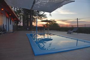 a swimming pool with a table and an umbrella at Pousada Vossa Excelência in Cajuru