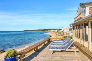 a deck with two beach chairs and the ocean at Beachfront Greenport Villa in Greenport
