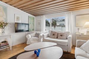 a living room with white furniture and a flat screen tv at Lovely Summer House Near Beach And Nature Spots in Hornbæk