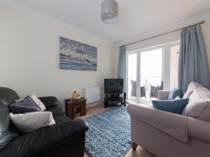 a living room with a couch and a television at Lower Chine Apartment in Shanklin