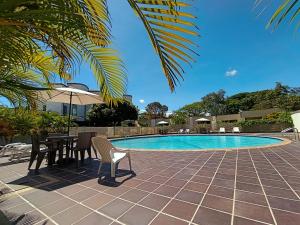 リカウルテにあるHotel TACALOA INN EXPERIENCEのプールサイドのパティオ(テーブル、椅子付)