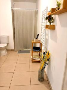 a bathroom with a toilet and a vase of flowers at Cosy T2 neuf avec balcon Proche centre & plage in Montpellier